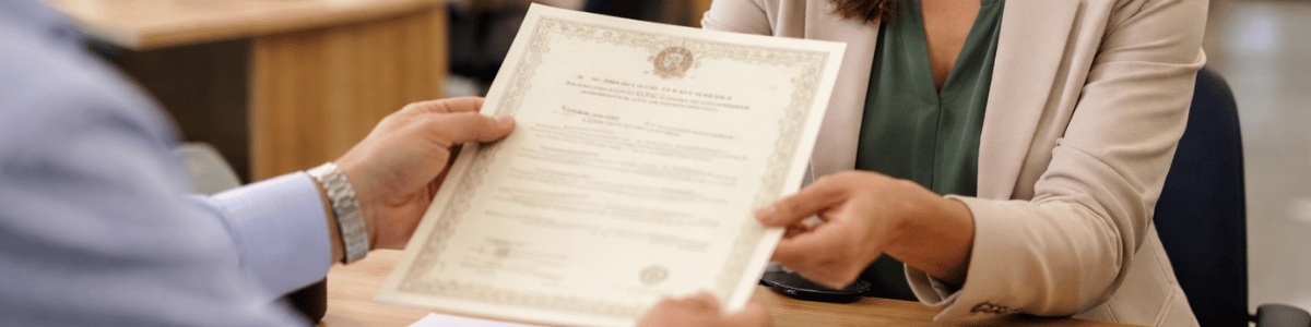 certidão de breve relato Pessoa em primeiro plano recebendo uma certidão das mãos de um atendente em um cartório, em um ambiente interno organizado e bem iluminado