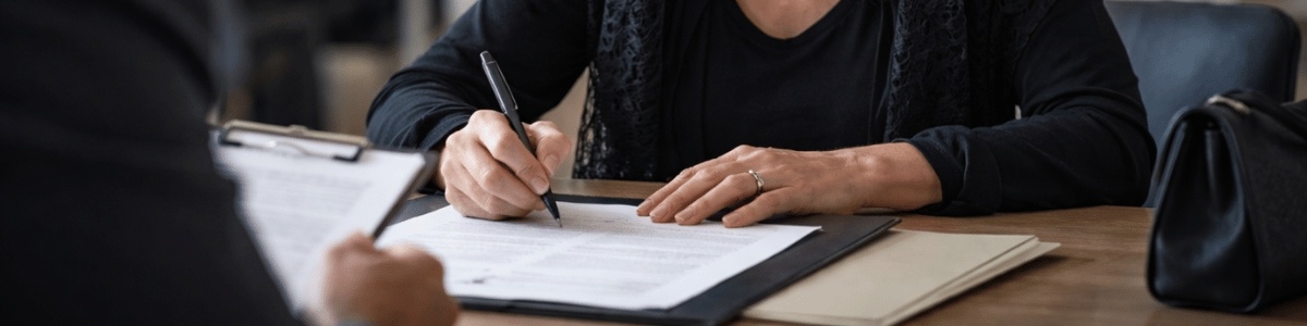 quando a pessoa fica viúva tem que mudar os documentos Mulher vestida de preto assina um documento sobre a mesa em um cartório, com expressão séria e concentrada