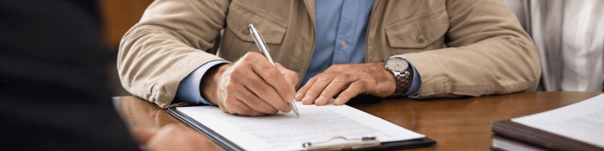 certidão de testamento Uma pessoa idosa assina um documento sobre a mesa de um cartório, com expressão concentrada e mãos firmes segurando a caneta