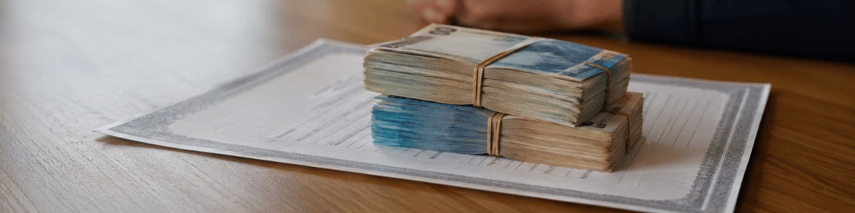 Certidão sobre a mesa com maços de dinheiro em destaque, em um ambiente interno realista e institucional, transmitindo curiosidade sobre valores, documentos e questões financeiras.