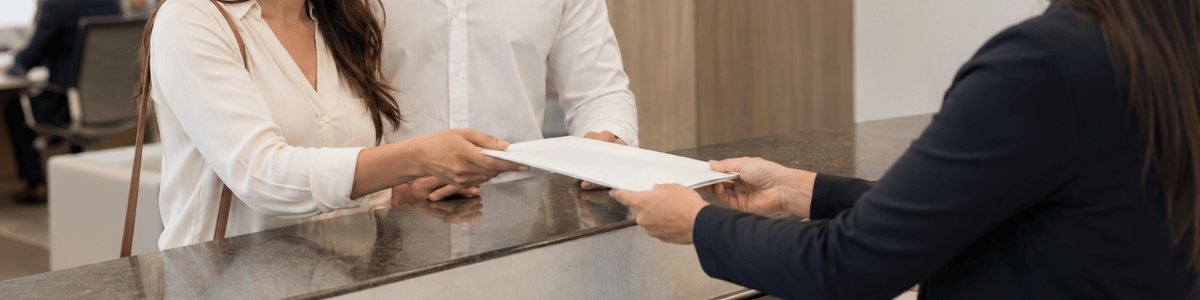 habilitação de casamento Casal sorridente recebendo um documento em um cartório moderno, com atendimento profissional e ambiente institucional, transmitindo expectativa e confiança para quem está iniciando o processo de casamento civil.