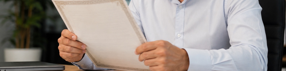 onde fica a matricula da certidão de casamento Homem analisando atentamente uma certidão em um ambiente de escritório, com expressão concentrada e iluminação natural. A cena transmite seriedade e cuidado na conferência do documento