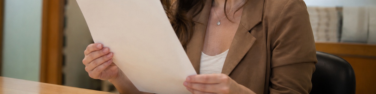 Uma mulher analisa atentamente uma certidão em um ambiente profissional, com iluminação suave e expressão concentrada