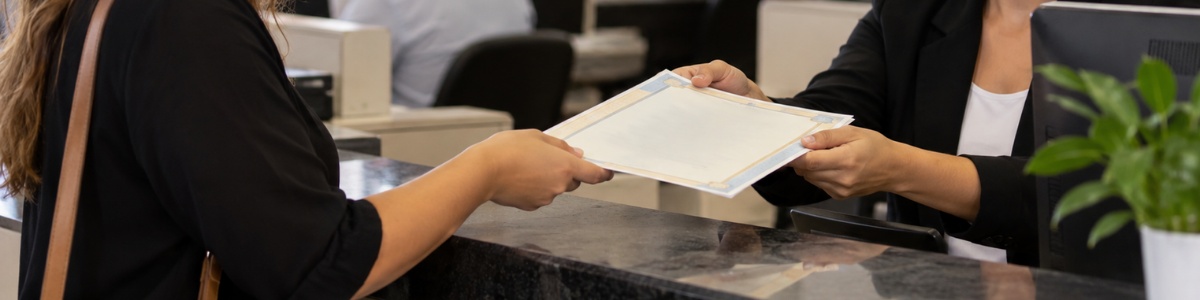 certidão de incapacidade civil Mulher recebendo uma certidão de uma atendente em cartório, em ambiente profissional, organizado e com iluminação natural.